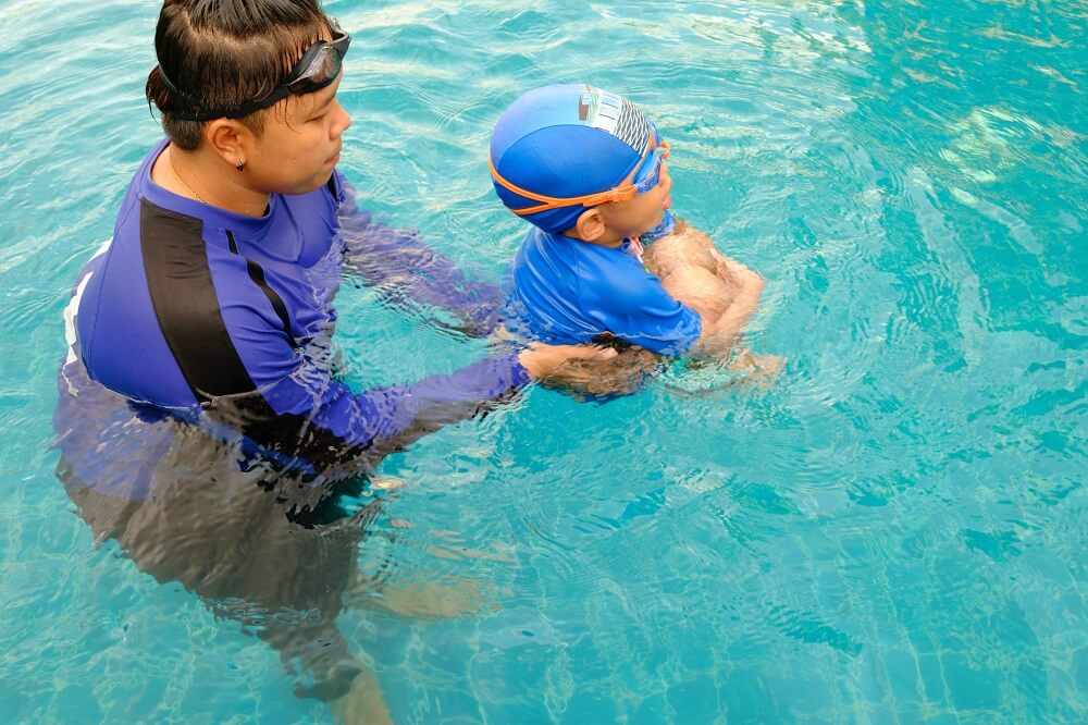 swim instructor teaching child how to swim